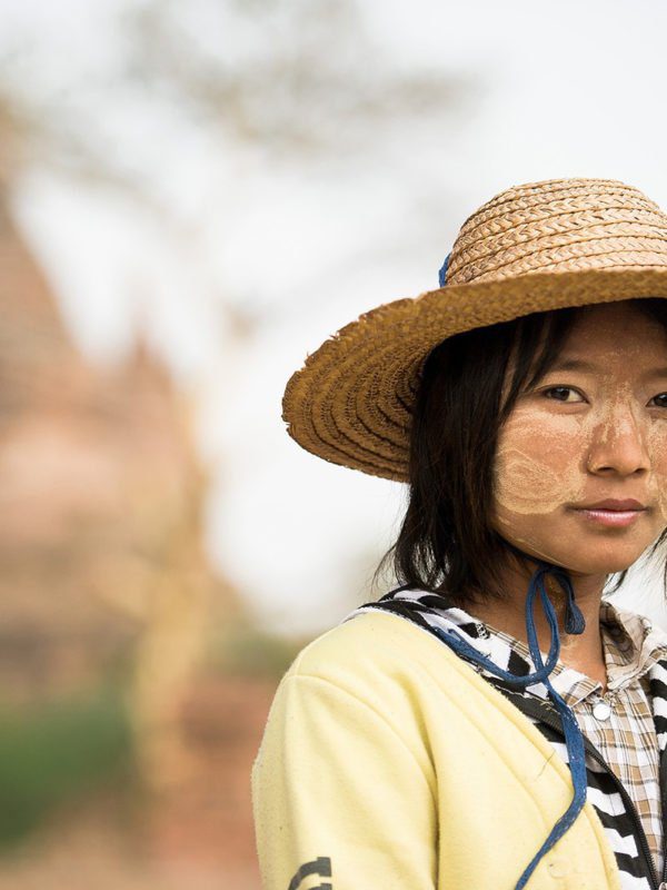 Femme arborant la peinture thanaka sur ses joues posant devant un temple de Bagan, Birmanie, Vietnam