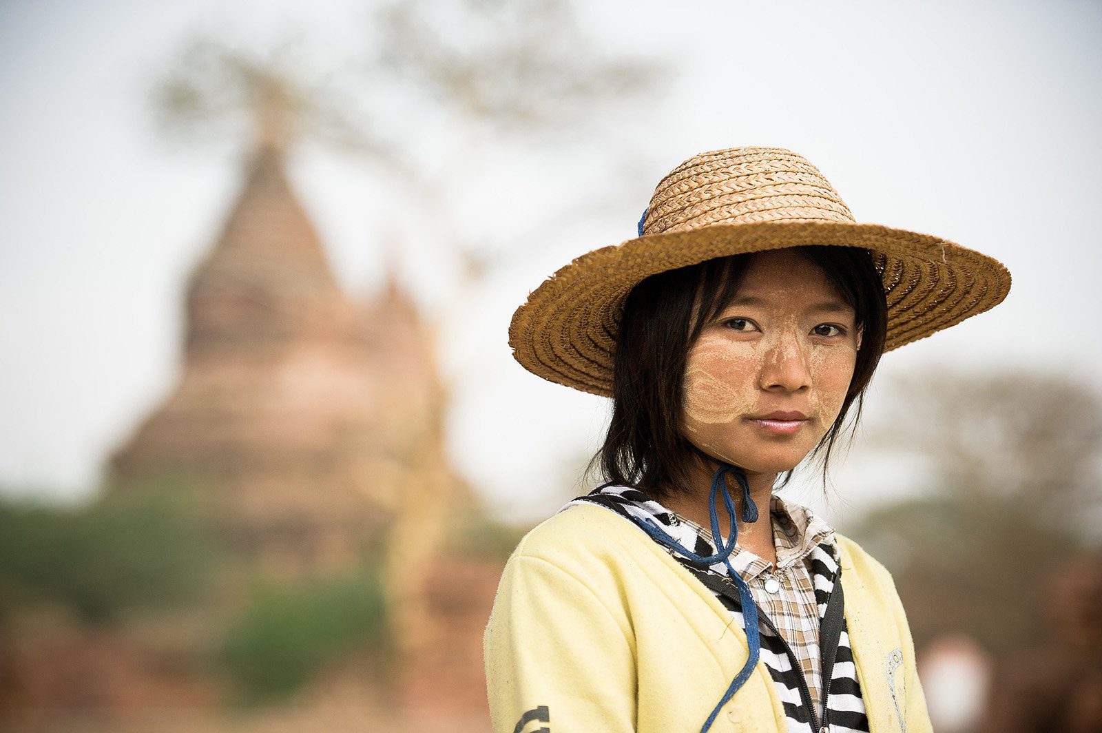 Femme arborant la peinture thanaka sur ses joues posant devant un temple de Bagan, Birmanie, Vietnam