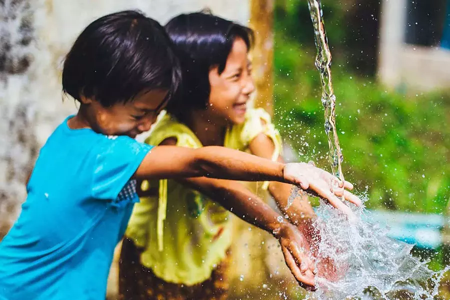 Enfants vietnamiens jouant et rigolant avec une fontaine à eau