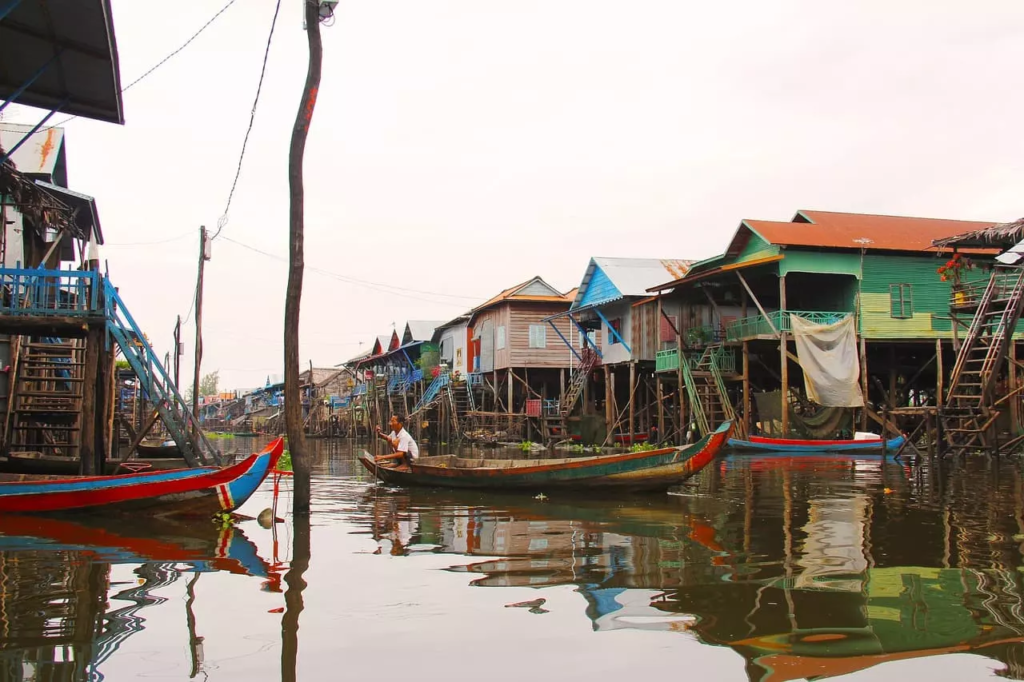 Habitant du Tonle Sap navigant en barque sur le lac, au milieu des habitations