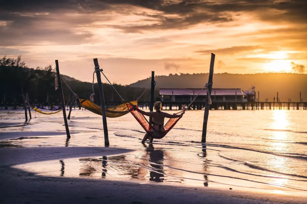 Femme dans un hamac regardant le coucher de soleil sur une plage du Cambodge