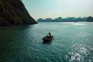 Pêcheur dans la baie d'Halong navigant sur un petit sampan