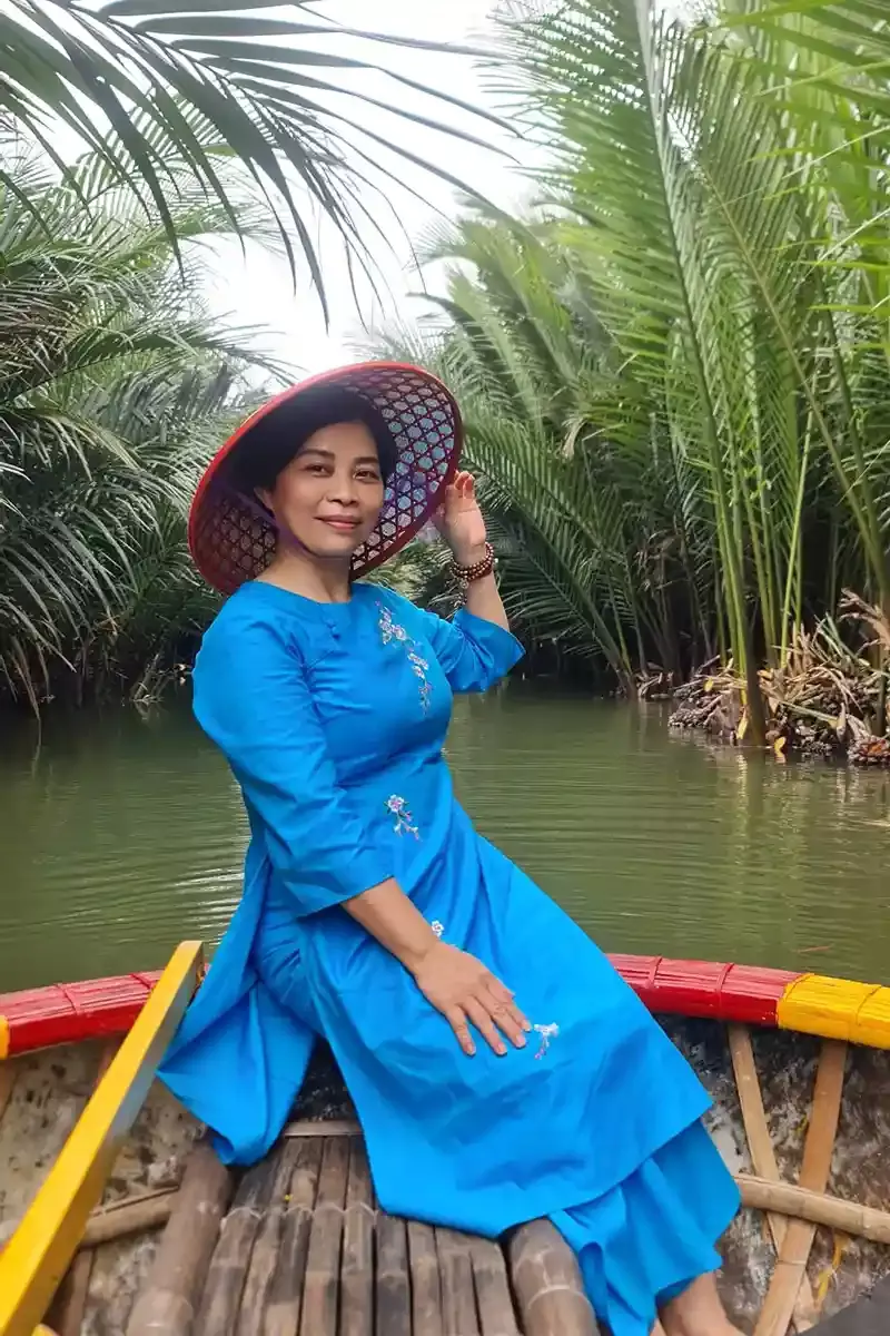 Mme Huong, directrice de Parfum d'Automne, posant sur un bateau en bambou à Hoi An, Vietnam